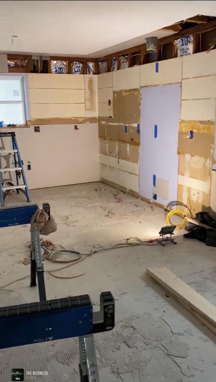 Kitchen renovation before — cabinets removed, open wall cavities, exposed subfloor, and tools on site